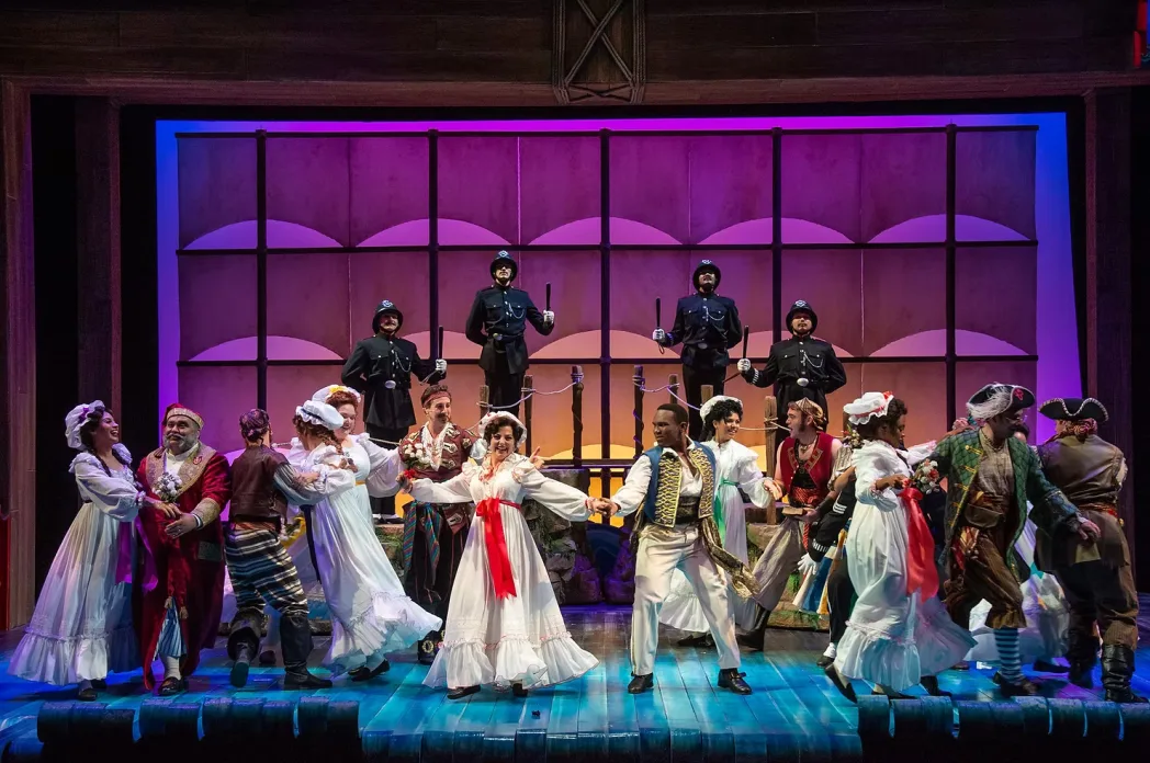 Stage image from The Pirates of Penzance showing bright operetta staging and ensemble movement.