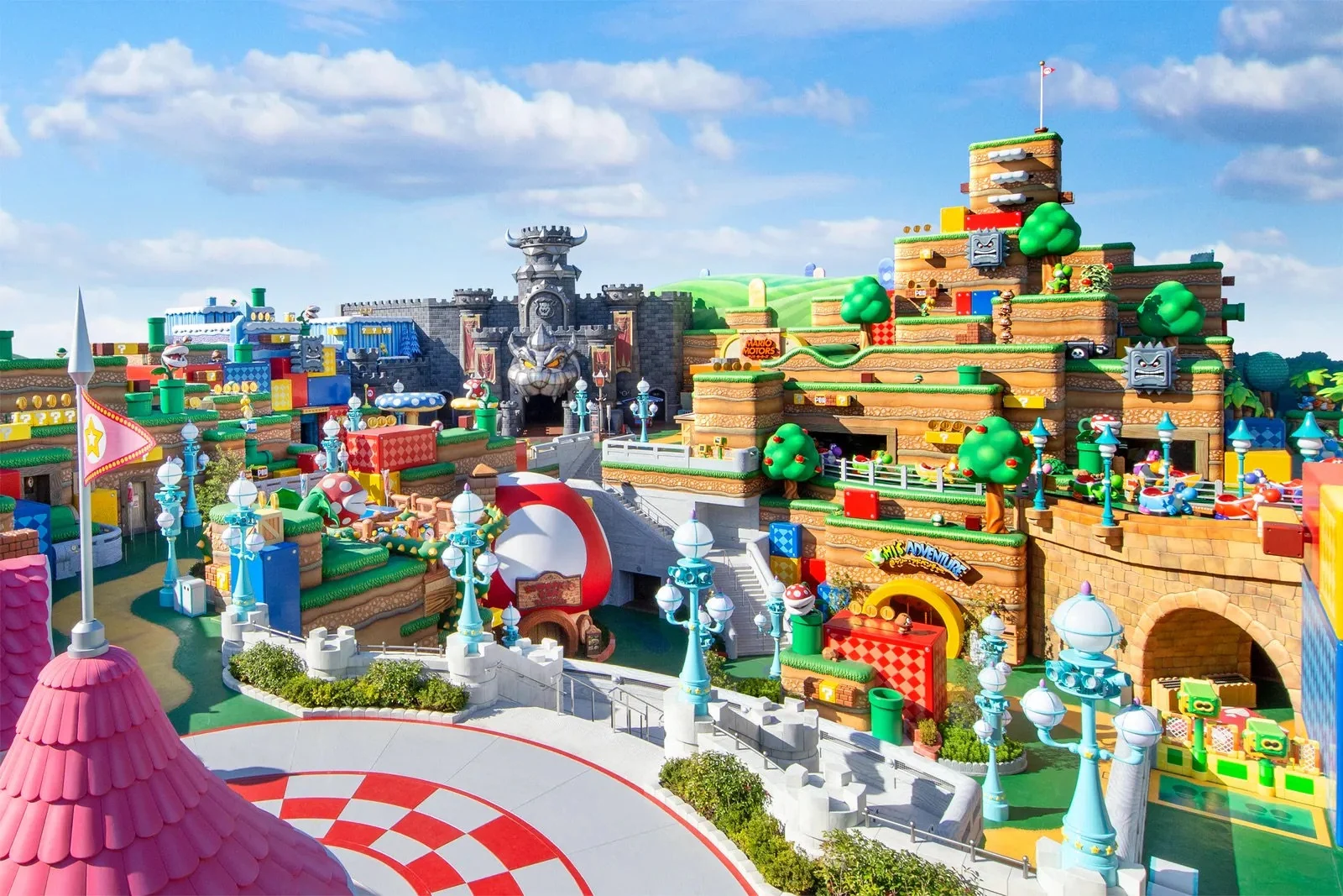 Guests walking through a colorful game-inspired themed land with stacked scenic architecture and character-scale details.