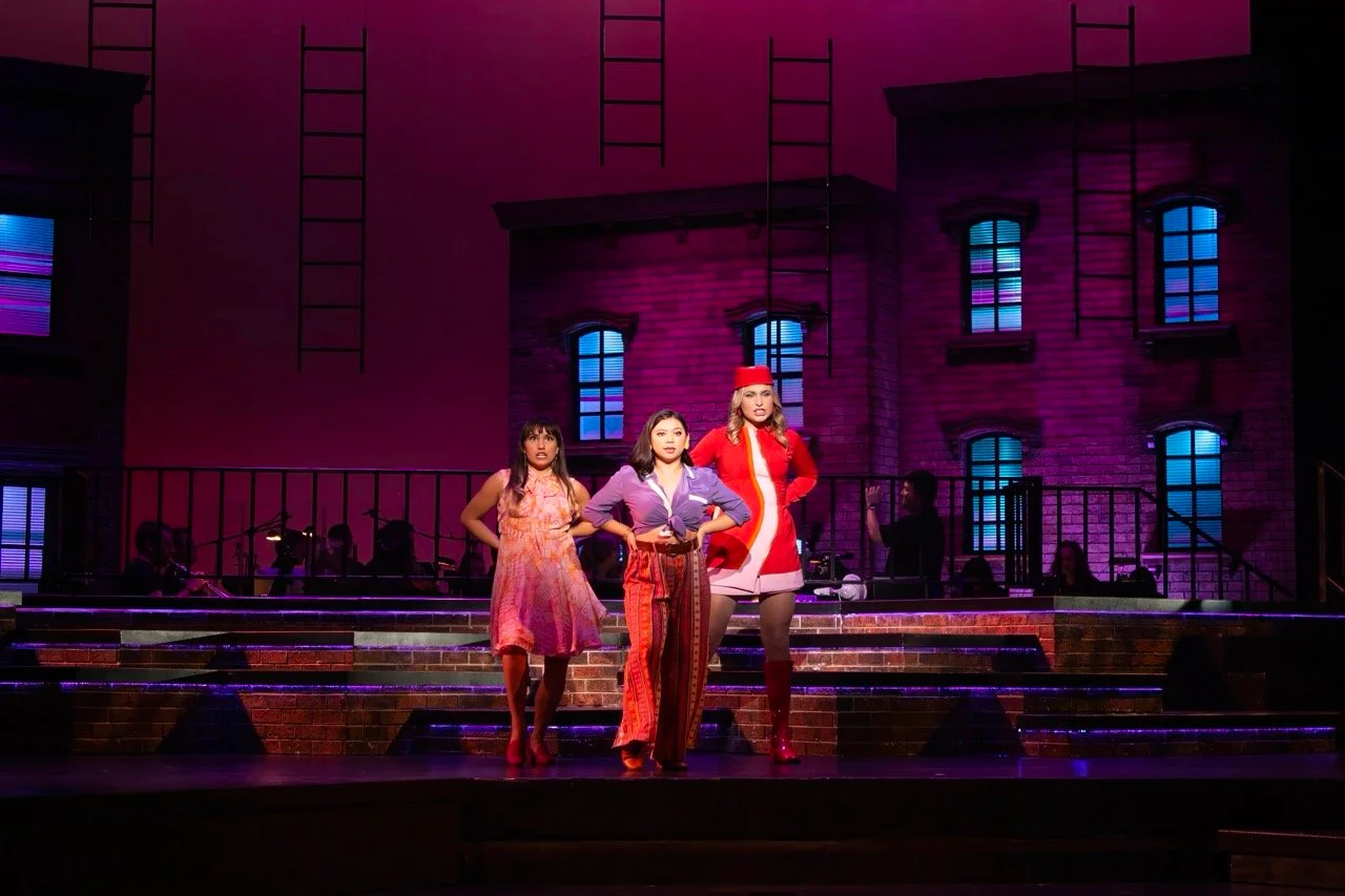 Production image from Company highlighting the exterior city world and embedded orchestra, scenic design by Brandon PT Davis.