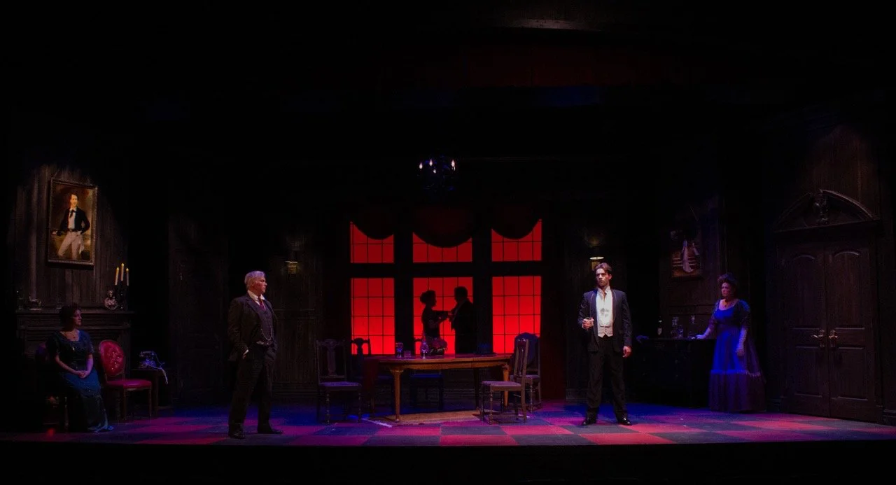 Production still from An Inspector Calls with actors framed by the controlled geometry of the set, scenic design by Brandon PT Davis.
