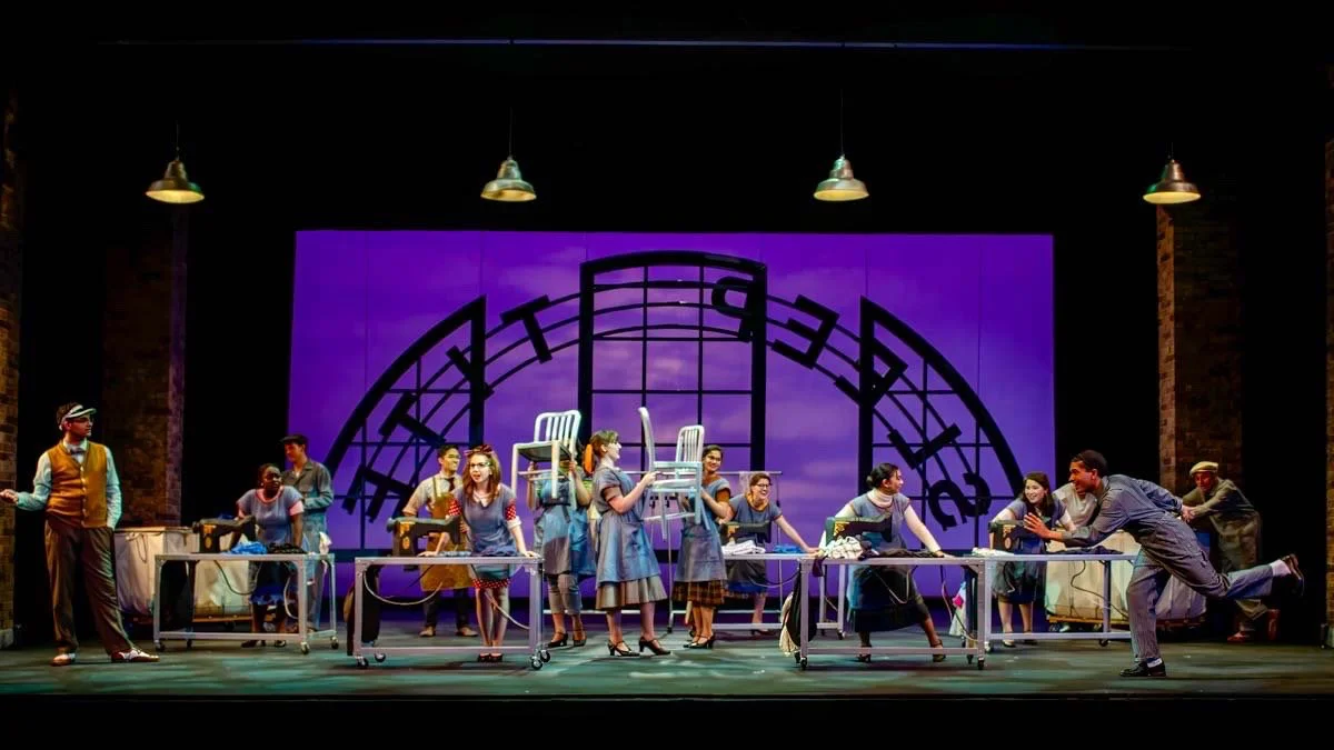 Production image from The Pajama Game highlighting signage and period workplace structure, scenic design by Brandon PT Davis.